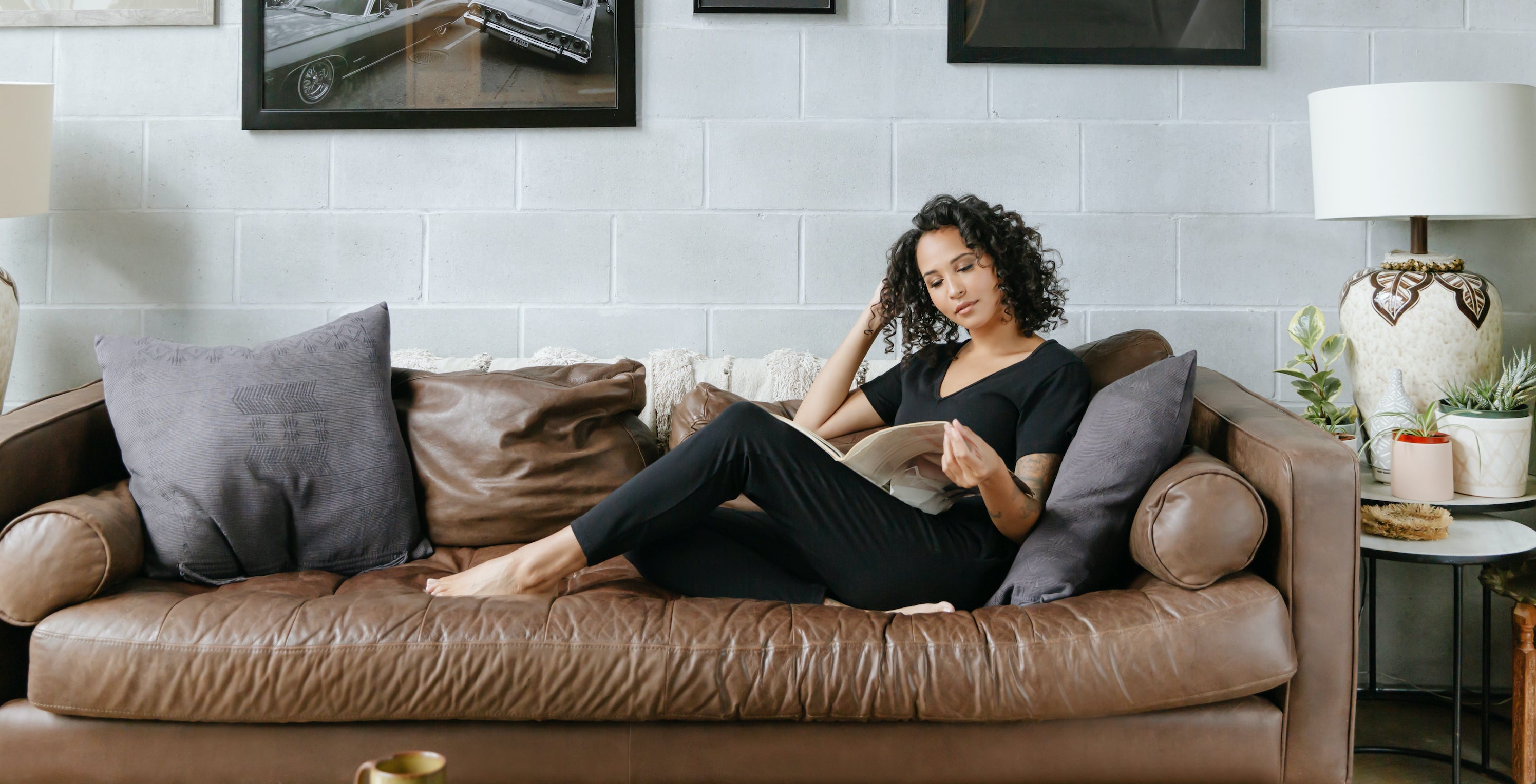 woman wearing the sunday romper in black on leather sofa