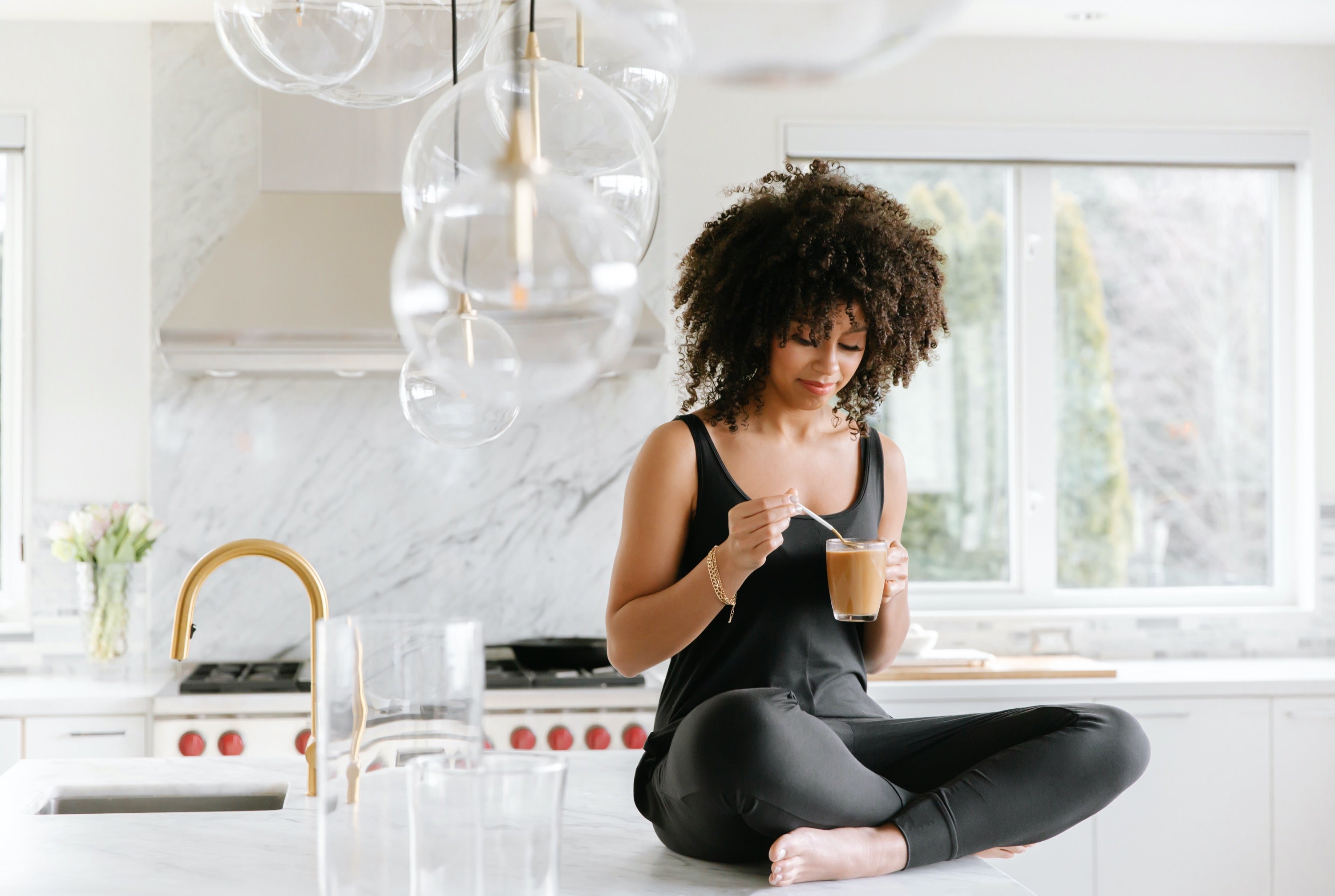 model drinking coffee wearing tuesday romper on kitchen counter